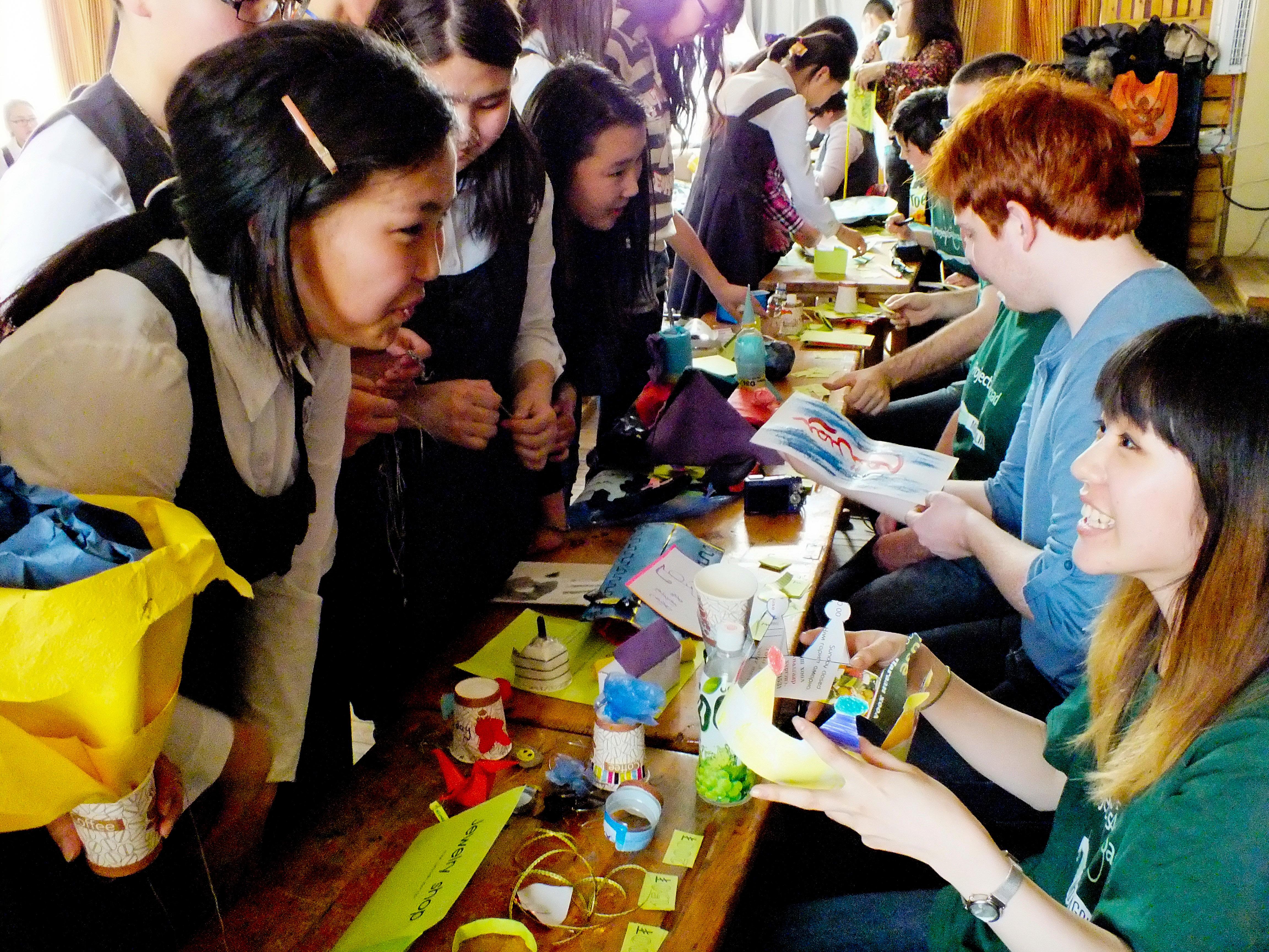Students line up to receive their crafts project from volunteers teaching in Mongolia Projects Abroad volunteers prepare a crafts table during their teaching work experience in Mongolia